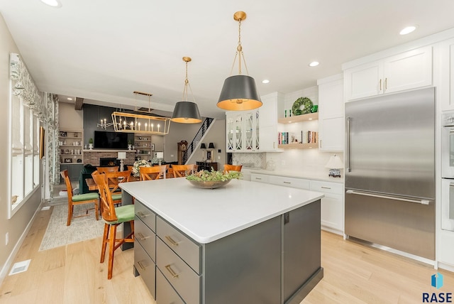 kitchen with glass insert cabinets, white cabinetry, stainless steel appliances, and a center island