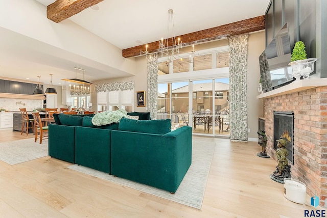 living room with beamed ceiling, a fireplace, light wood-style flooring, and an inviting chandelier