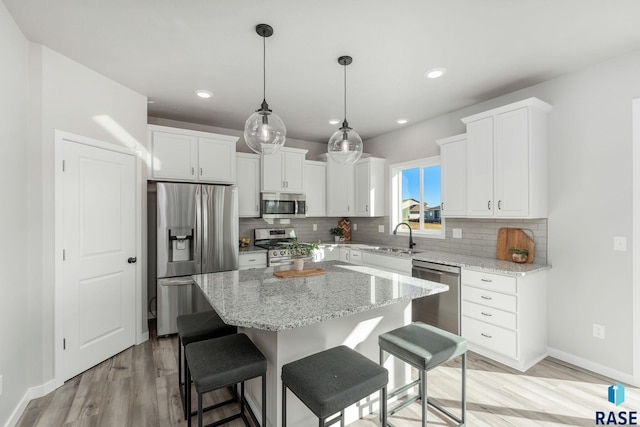 kitchen with a center island, white cabinets, stainless steel appliances, and sink