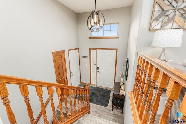 foyer entrance with a towering ceiling, light hardwood / wood-style flooring, and an inviting chandelier