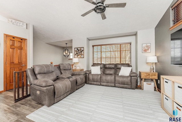 living room with ceiling fan, light hardwood / wood-style floors, and a textured ceiling