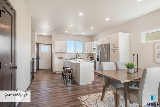 kitchen featuring a breakfast bar, white cabinets, stainless steel fridge, and a center island