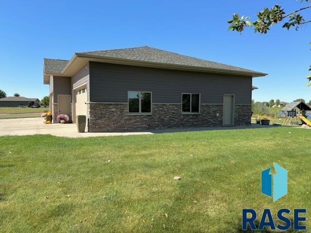 view of side of property with a playground, a garage, and a lawn