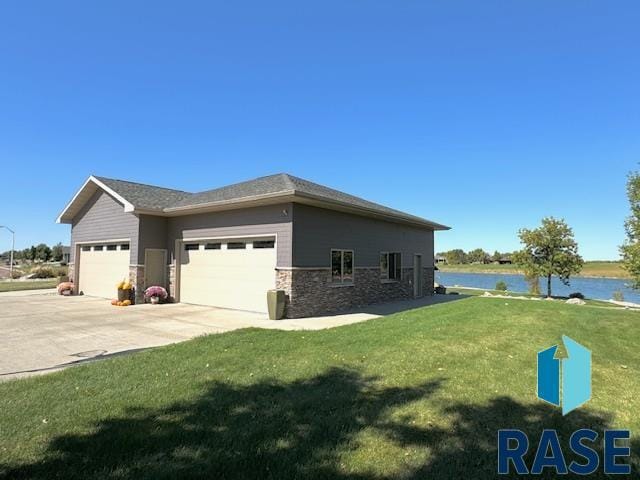 view of side of home featuring a yard, a water view, and a garage