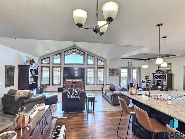 living room with wood-type flooring, ceiling fan with notable chandelier, plenty of natural light, and lofted ceiling