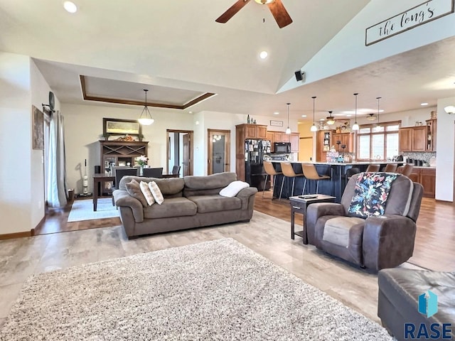 living room with ceiling fan, light hardwood / wood-style flooring, and a tray ceiling