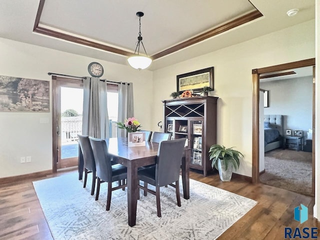 dining room with wood-type flooring, crown molding, and a tray ceiling