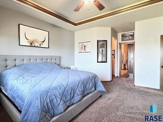 bedroom featuring carpet, a tray ceiling, ceiling fan, and crown molding