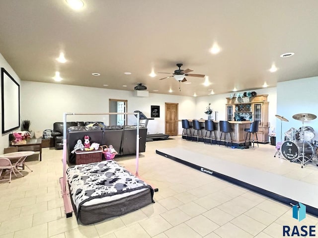 interior space with bar, ceiling fan, and light tile patterned flooring