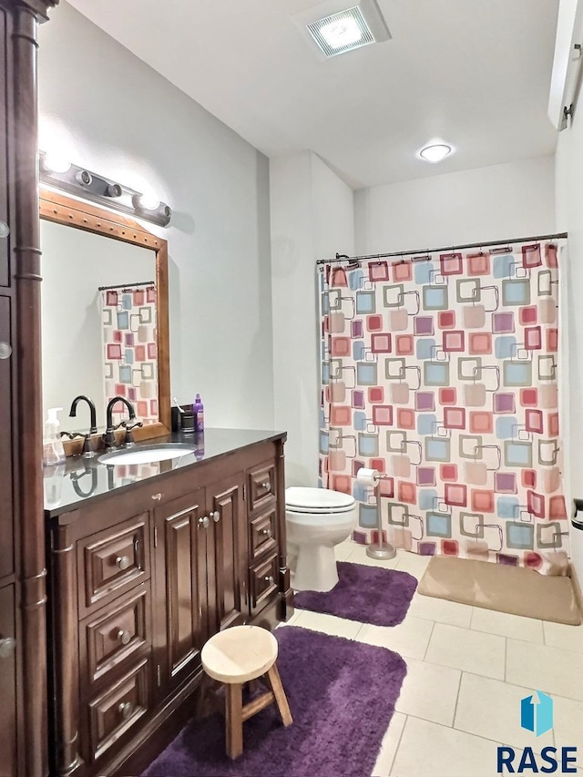 bathroom with toilet, vanity, tile patterned floors, and walk in shower