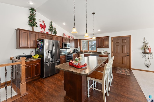 kitchen featuring dark hardwood / wood-style flooring, lofted ceiling, a kitchen bar, a kitchen island, and appliances with stainless steel finishes