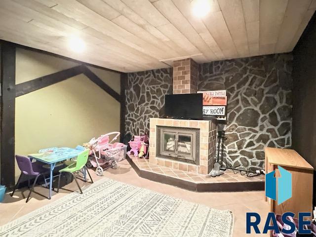 game room with a fireplace and wood ceiling