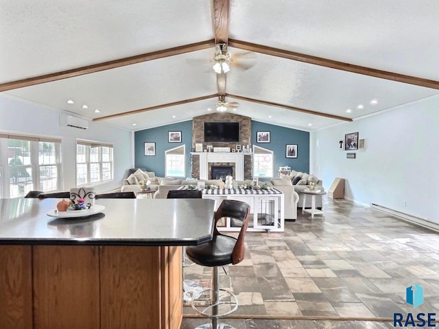 kitchen featuring a large fireplace, a wall mounted AC, ceiling fan, lofted ceiling with beams, and a large island