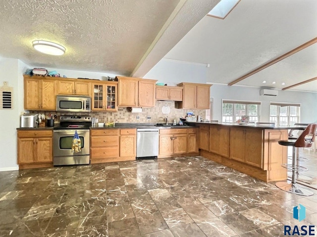 kitchen featuring a wall mounted air conditioner, decorative backsplash, stainless steel appliances, sink, and a breakfast bar area