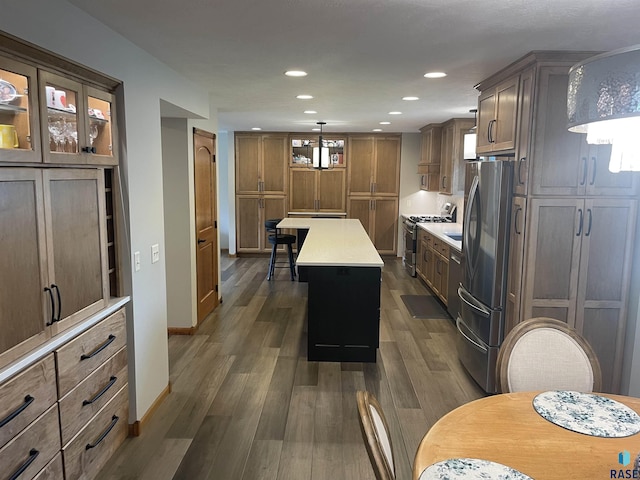 kitchen featuring dark hardwood / wood-style flooring, a kitchen island, stainless steel appliances, and decorative light fixtures