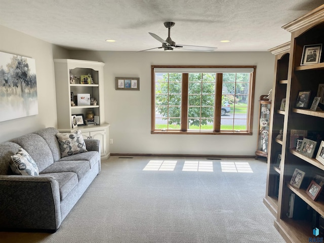 carpeted living room with ceiling fan and a textured ceiling