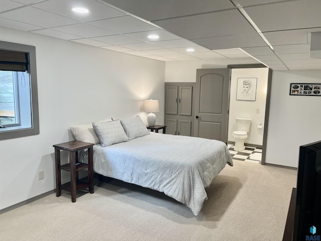 bedroom featuring ensuite bath, light carpet, and a paneled ceiling