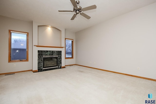 unfurnished living room with a high end fireplace, carpet, and ceiling fan