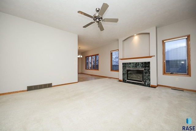 unfurnished living room with carpet flooring, ceiling fan with notable chandelier, and a fireplace