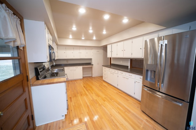 kitchen featuring stainless steel fridge, sink, light hardwood / wood-style flooring, butcher block countertops, and white cabinetry