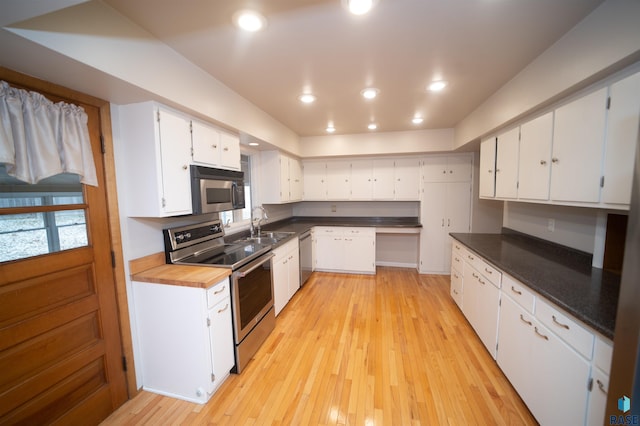 kitchen featuring appliances with stainless steel finishes, light hardwood / wood-style floors, white cabinetry, and sink