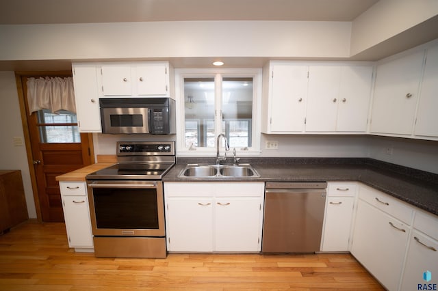 kitchen with sink, white cabinets, stainless steel appliances, and light hardwood / wood-style flooring