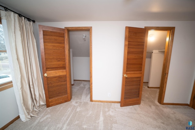 unfurnished bedroom with light carpet, a walk in closet, and a closet