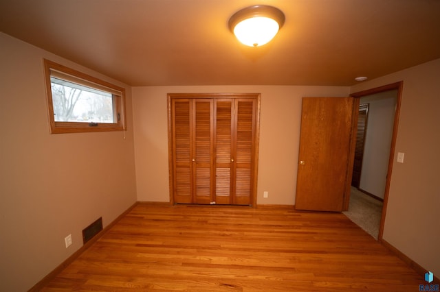 unfurnished bedroom with light hardwood / wood-style flooring and a closet