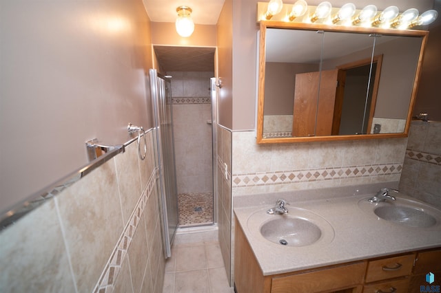 bathroom featuring tile patterned flooring, vanity, a shower with shower door, and tile walls