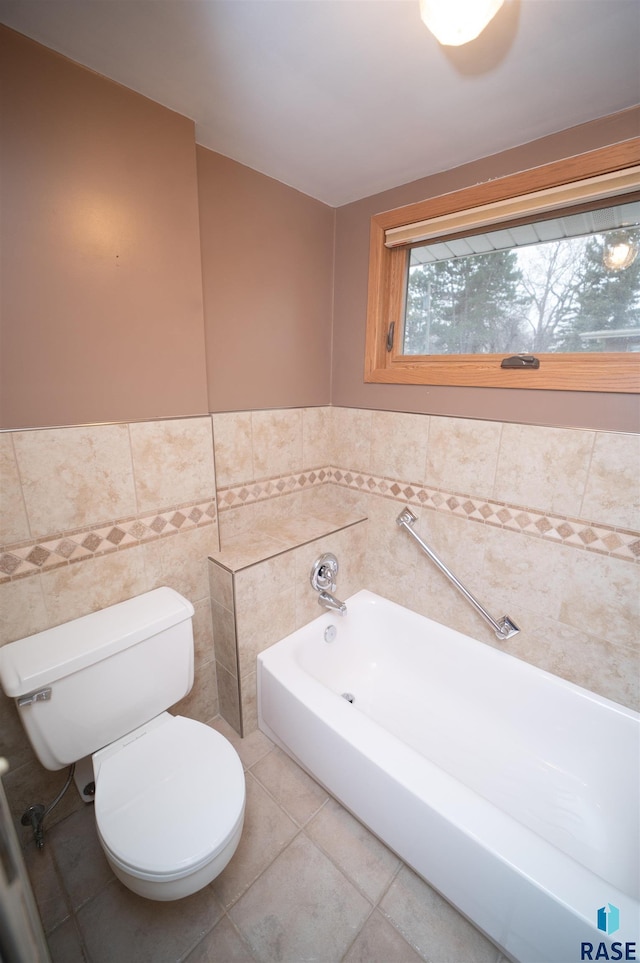 bathroom with tile patterned floors, a tub to relax in, tile walls, and toilet