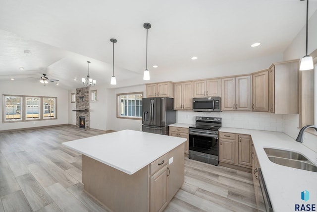 kitchen featuring appliances with stainless steel finishes, tasteful backsplash, ceiling fan with notable chandelier, vaulted ceiling, and sink