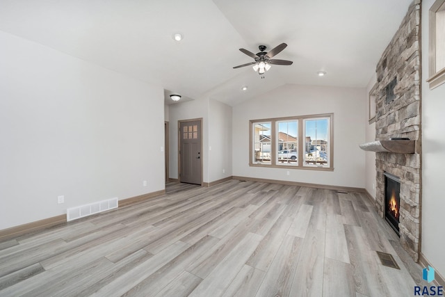 unfurnished living room featuring light hardwood / wood-style flooring, a stone fireplace, ceiling fan, and lofted ceiling