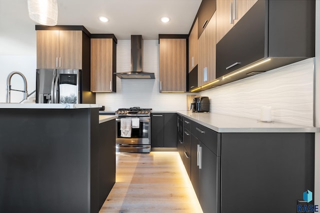 kitchen with appliances with stainless steel finishes, pendant lighting, wall chimney exhaust hood, and modern cabinets