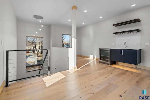 bar with beverage cooler, wet bar, light wood-style floors, a sink, and recessed lighting