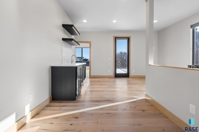 kitchen featuring light countertops, light wood-type flooring, plenty of natural light, and dark cabinets