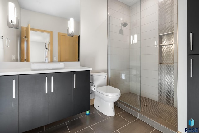 full bath featuring toilet, tiled shower, vanity, and tile patterned floors