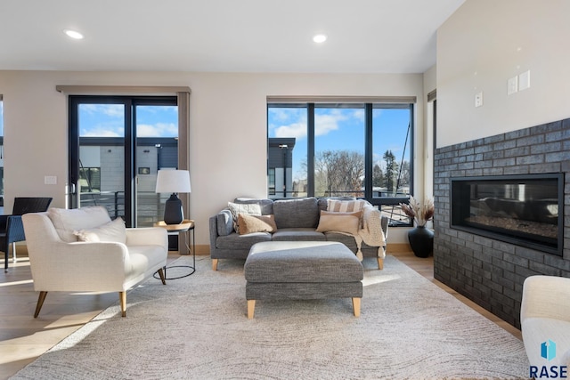 living room with a brick fireplace, light wood-style flooring, a wealth of natural light, and recessed lighting