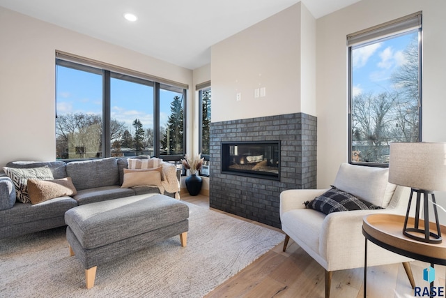 living room featuring recessed lighting, a fireplace, plenty of natural light, and light wood finished floors