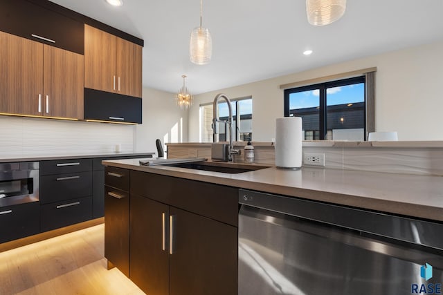 kitchen featuring dishwashing machine, modern cabinets, a sink, and decorative light fixtures