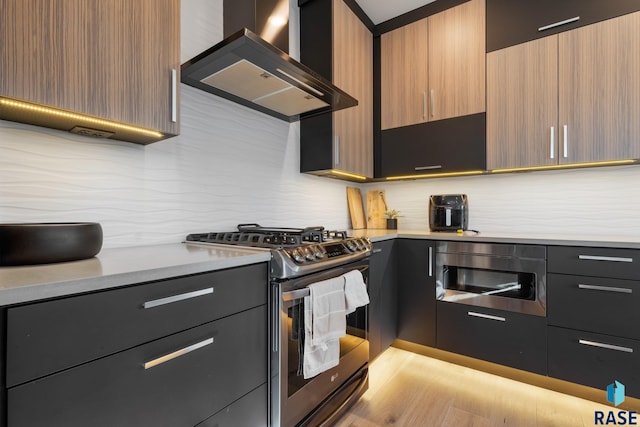 kitchen with stainless steel appliances, tasteful backsplash, light wood-style flooring, modern cabinets, and wall chimney exhaust hood