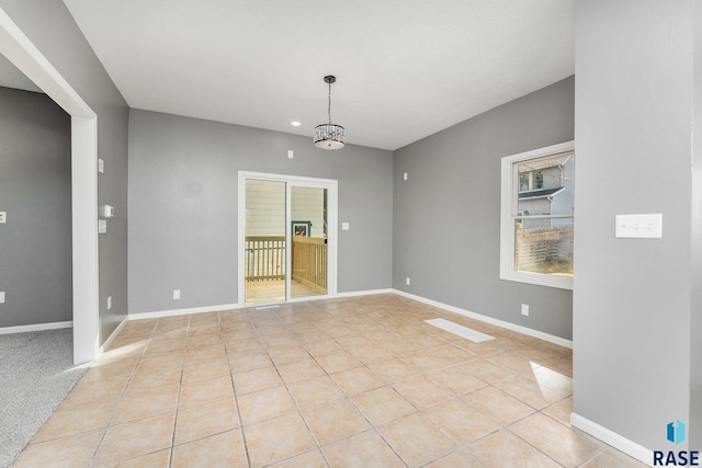 tiled empty room featuring a chandelier