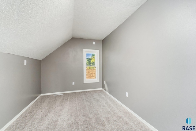 bonus room featuring light colored carpet, a textured ceiling, and vaulted ceiling