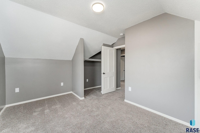 bonus room with a textured ceiling, light carpet, and vaulted ceiling