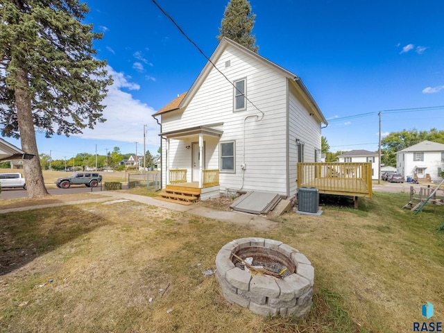 back of house featuring a yard, central air condition unit, an outdoor fire pit, and a wooden deck