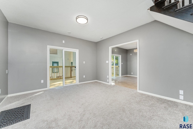 carpeted empty room featuring lofted ceiling