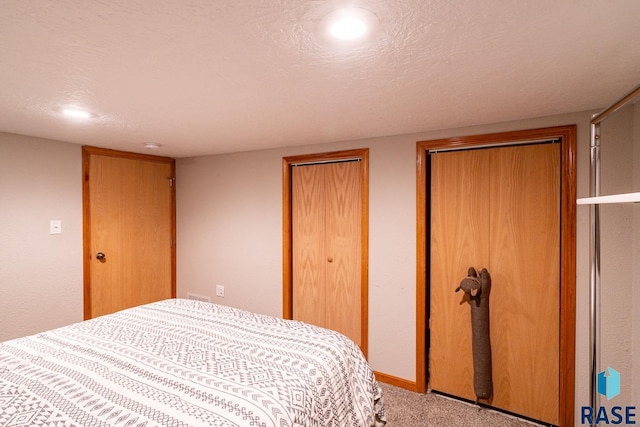 carpeted bedroom featuring a textured ceiling and two closets