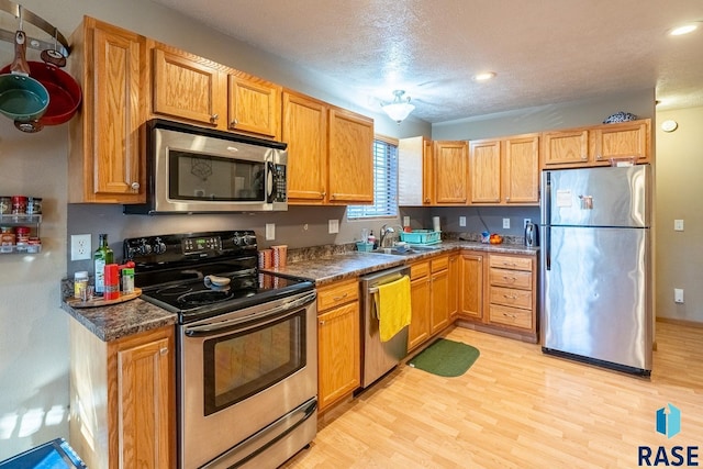 kitchen with a textured ceiling, light hardwood / wood-style floors, sink, and appliances with stainless steel finishes