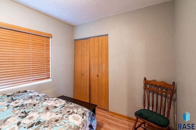 bedroom with a closet, a textured ceiling, and light hardwood / wood-style flooring