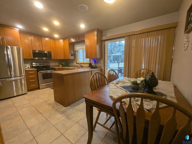 kitchen featuring kitchen peninsula, appliances with stainless steel finishes, light tile patterned flooring, and sink