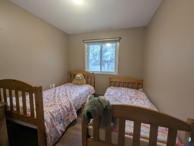 bedroom with dark hardwood / wood-style floors and a textured ceiling